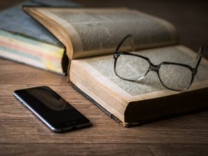 Open book with reading glasses and iPhone